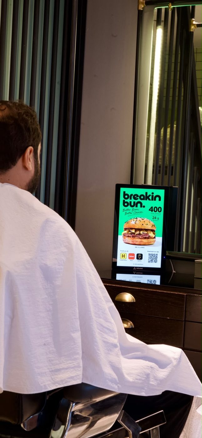 A customer in the chair at Leather Chair facing an AdLevel screen
